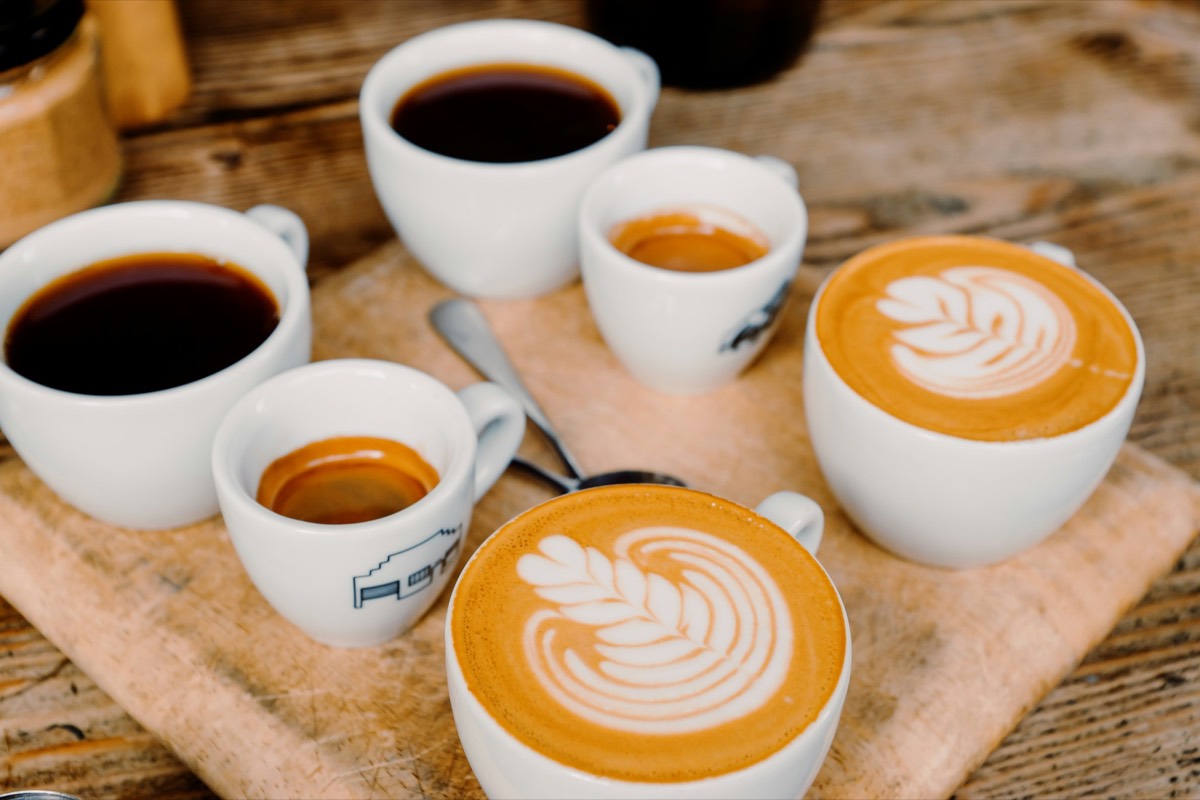 Träbricka med flera koppar kaffe — bryggkaffe, espresso och latte med konst — Kafé Norr